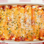 Chicken Enchiladas with red sauce in a white baking dish for dinner.