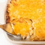 A serving spoon inserted into a casserole dish for CopyCat Cracker Barrel Hash Brown Casserole.