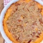 A picture of a whole Cracker Barrel Sweet Potato Casserole Recipe on a gingham cloth and a wood pallet.