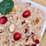 A white bowl filled with a Cranberry Rice Recipe, sliced almonds, dried cranberries, and fresh cranberries.